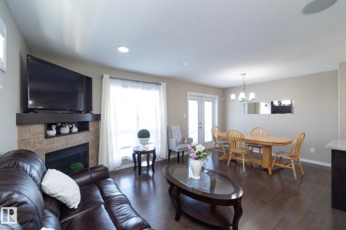 Inviting living space featuring dark hardwood flooring, a tiled fireplace, and recessed lighting - 132 Kirpatrick Way, Leduc, AB - Indoor Photo Showing Living Room With Fireplace