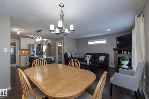 The property features a dining area with a wooden table, dark wood flooring, and a brushed nickel chandelier - 132 Kirpatrick Way, Leduc, AB - Indoor Photo Showing Dining Room