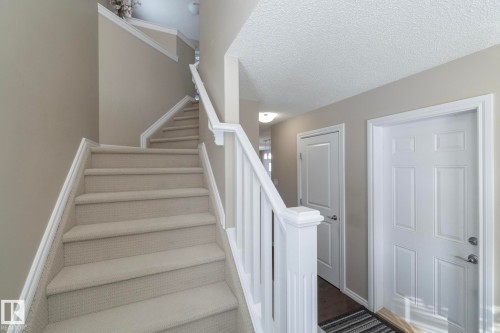 Entryway featuring a carpeted staircase with white railings, light neutral wall paint, and white paneled doors - 132 Kirpatrick Way, Leduc, AB - Indoor Photo Showing Other Room