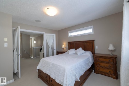 This bedroom features carpeted flooring, a ceiling light fixture, and a window providing natural light - 132 Kirpatrick Way, Leduc, AB - Indoor Photo Showing Bedroom