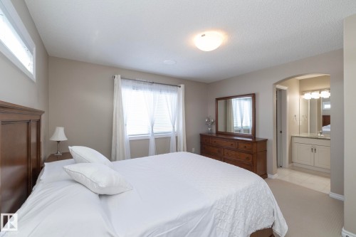 The property features a bedroom with neutral-toned walls, carpeting, and a window with blinds and sheer curtains - 132 Kirpatrick Way, Leduc, AB - Indoor Photo Showing Bedroom