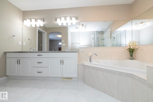 The bathroom features a double vanity with white cabinetry and a light-colored countertop, along with a built-in bathtub with tiled surround - 132 Kirpatrick Way, Leduc, AB - Indoor Photo Showing Bathroom