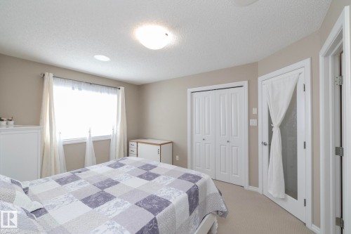 This inviting room features a window with white curtains, neutral-toned walls, and carpeted flooring - 132 Kirpatrick Way, Leduc, AB - Indoor Photo Showing Bedroom