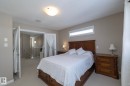 The property features a bedroom with neutral-toned walls and carpeting, a wooden bed frame, and a horizontal window - 132 Kirpatrick Way, Leduc, AB  - Indoor Photo Showing Bedroom 