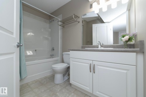 The bathroom features a vanity with a white cabinet, a built-in sink, and a mirror with overhead lighting - 132 Kirpatrick Way, Leduc, AB - Indoor Photo Showing Bathroom