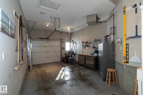 The property features a garage with a roll-up door, a utility sink, and a work surface - 132 Kirpatrick Way, Leduc, AB - Indoor Photo Showing Garage