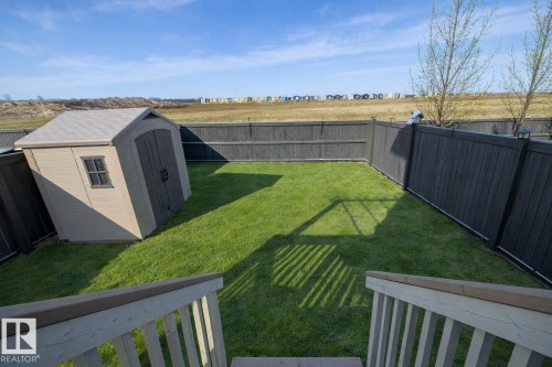 The backyard features a well-maintained lawn, a storage shed, and a privacy fence - 132 Kirpatrick Way, Leduc, AB - Outdoor