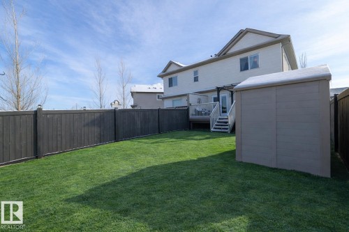 The property features a spacious yard with a well-maintained lawn and a dark wood fence - 132 Kirpatrick Way, Leduc, AB - Outdoor