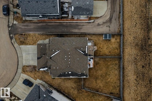 The property features a large yard with a fence and a paved driveway leading to the home - 132 Kirpatrick Way, Leduc, AB - 