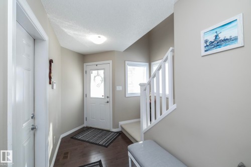 Inviting entryway featuring dark wood flooring, a white front door with a window, and a staircase with white railings - 132 Kirpatrick Way, Leduc, AB - Indoor Photo Showing Other Room