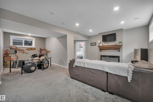 Spacious room with gray carpeting, recessed lighting, and a window providing natural light - 316 Avena Link, Leduc, AB - Indoor With Fireplace