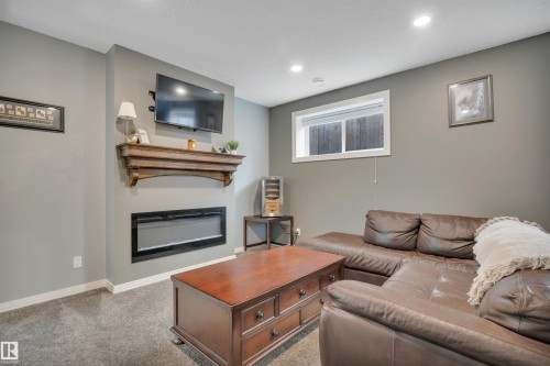 Living space featuring gray walls, carpeted flooring, and an electric fireplace with a wooden mantel - 316 Avena Link, Leduc, AB - Indoor Photo Showing Living Room With Fireplace
