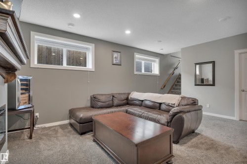The property features a cozy living area with neutral gray walls, recessed lighting, and soft carpet flooring - 316 Avena Link, Leduc, AB - Indoor
