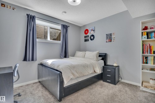 This room features light grey walls and carpet flooring, with a window fitted with dark grey drapes - 316 Avena Link, Leduc, AB - Indoor Photo Showing Bedroom