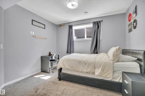 The room features light gray walls, a window with dark gray curtains, and a ceiling light fixture - 316 Avena Link, Leduc, AB - Indoor Photo Showing Bedroom