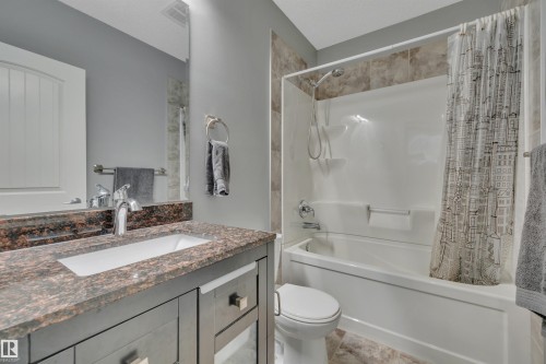 Bathroom featuring a vanity with a dark granite countertop, an undermount sink, and a combination bathtub and shower - 316 Avena Link, Leduc, AB - Indoor Photo Showing Bathroom