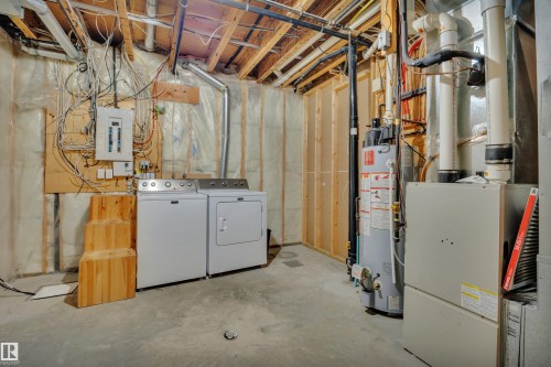 This area of the property includes exposed ceiling joists, a washer and dryer, and visible utility systems - 316 Avena Link, Leduc, AB - Indoor Photo Showing Laundry Room