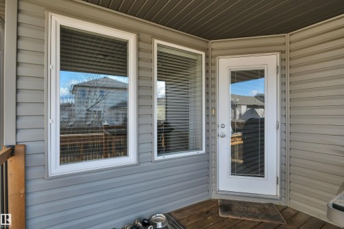 The property features an outdoor patio with a wooden deck, a full-light exterior door, and two windows with blinds - 316 Avena Link, Leduc, AB - Outdoor With Deck Patio Veranda With Exterior