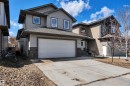 The property features a two-story exterior with grey siding and stone detailing, a two-car garage, and a concrete driveway - 316 Avena Link, Leduc, AB  - Outdoor With Facade 