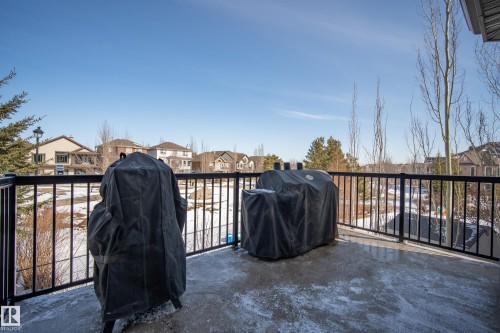 The property features a concrete deck with black metal railings, overlooking a landscaped area with trees and views of other properties - 20714 56A Avenue, Edmonton, AB - Outdoor