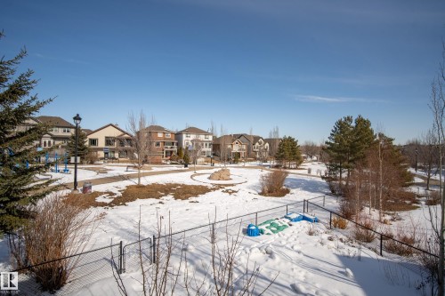 A community green space featuring mature trees, paved pathways, and an open lawn area, with residential properties visible in the background - 20714 56A Avenue, Edmonton, AB - Outdoor