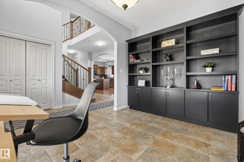 This versatile space features a large dark built-in shelving unit with cabinets, providing extensive storage and display options - 20714 56A Avenue, Edmonton, AB - Indoor