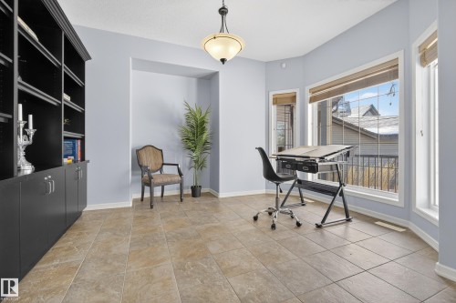 This room features large windows, tiled flooring, and a built-in shelving unit with lower cabinetry - 20714 56A Avenue, Edmonton, AB - Indoor