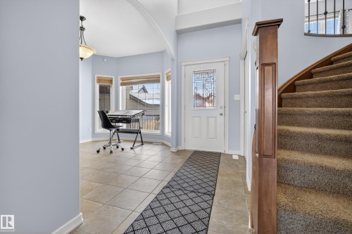 Inviting entryway featuring a leaded glass front door, a curved staircase with carpeted treads, and tiled flooring - 20714 56A Avenue, Edmonton, AB - Indoor Photo Showing Other Room