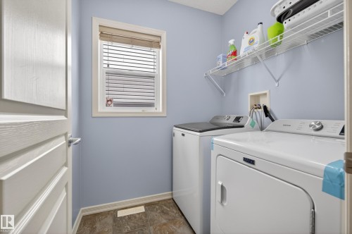 Utility room with a window, tile flooring, and a storage shelf - 20714 56A Avenue, Edmonton, AB - Indoor Photo Showing Laundry Room