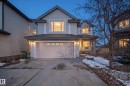 The property features a light-colored siding exterior, an attached garage with a concrete driveway, and a front porch with a railing - 20714 56A Avenue, Edmonton, AB  - Outdoor 