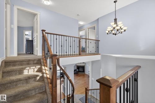 The property features a staircase with carpeted treads and a wooden handrail with decorative metal spindles - 20714 56A Avenue, Edmonton, AB - Indoor Photo Showing Other Room