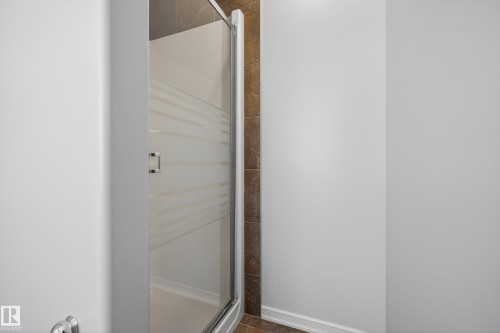 Shower enclosure with frosted glass door and brown tiled walls - 20714 56A Avenue, Edmonton, AB - Indoor