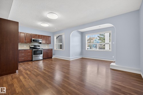 Open concept living area featuring hardwood flooring, light blue walls, and an arched doorway - 20714 56A Avenue, Edmonton, AB - Indoor Photo Showing Kitchen