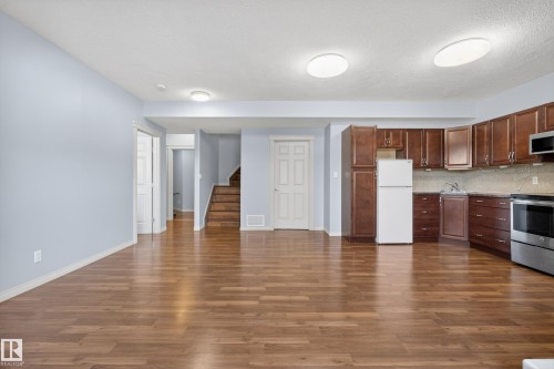 Open concept living area with hardwood floors, a kitchen featuring wood cabinetry, and stainless steel appliances - 20714 56A Avenue, Edmonton, AB - Indoor Photo Showing Kitchen