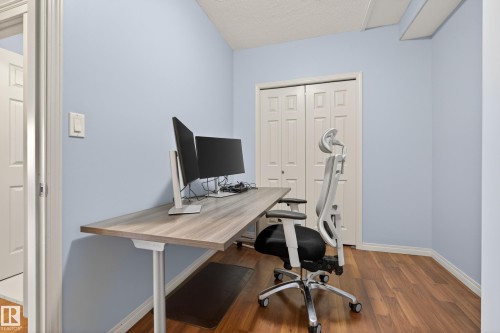 Room featuring hardwood floors, light blue walls, and a closet with bifold doors - 20714 56A Avenue, Edmonton, AB - Indoor Photo Showing Office