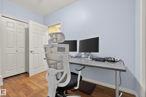 This room features hardwood flooring, light blue painted walls, and white bi-fold closet doors - 20714 56A Avenue, Edmonton, AB - Indoor Photo Showing Office