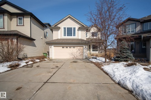 The property features a light-colored exterior with a front-facing garage and a concrete driveway - 20714 56A Avenue, Edmonton, AB - Outdoor