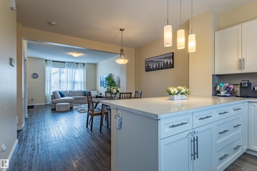 The property features a kitchen with white cabinetry, a light-colored countertop, and a tiled backsplash - 2679 Maple Way, Edmonton, AB - Indoor Photo Showing Kitchen