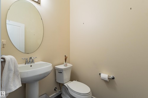 Bathroom with a pedestal sink, a toilet, and an oval mirror - 2679 Maple Way, Edmonton, AB - Indoor Photo Showing Bathroom