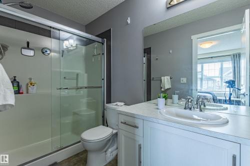 The bathroom features a spacious shower with glass sliding doors, a toilet, and a vanity with a white countertop and a single sink - 2679 Maple Way, Edmonton, AB - Indoor Photo Showing Bathroom