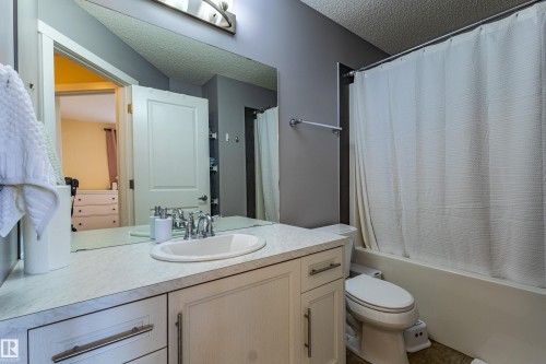 This bathroom features a vanity with an integrated sink, a large mirror, and a bathtub with a shower - 2679 Maple Way, Edmonton, AB - Indoor Photo Showing Bathroom