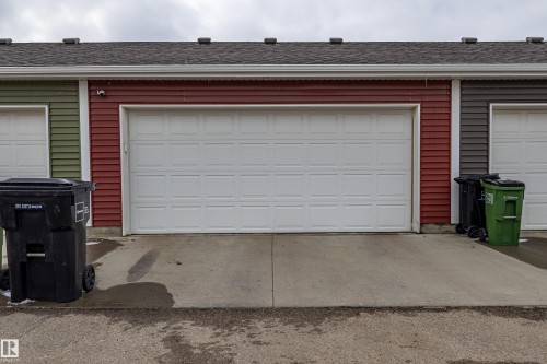 The property features an attached garage with a white panel door and red siding - 2679 Maple Way, Edmonton, AB - Outdoor With Exterior