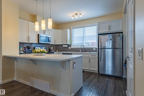 The kitchen features white cabinetry, a stainless steel refrigerator, and a built-in microwave - 2679 Maple Way, Edmonton, AB - Indoor Photo Showing Kitchen With Upgraded Kitchen