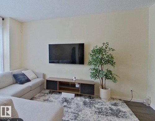 Living area featuring a light-colored sectional, light-colored walls, and a textured area rug - 2679 Maple Way, Edmonton, AB - Indoor Photo Showing Living Room
