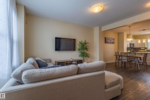Living area featuring light-colored walls and dark flooring, with a view into the dining area and kitchen - 2679 Maple Way, Edmonton, AB - Indoor Photo Showing Living Room