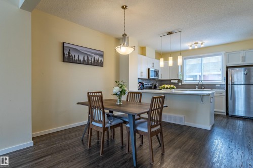 Open concept dining area and kitchen featuring dark wood-style flooring and light-colored walls - 2679 Maple Way, Edmonton, AB - Indoor