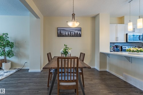 Dining area featuring dark wood flooring, a decorative chandelier, and a breakfast bar overlooking the kitchen - 2679 Maple Way, Edmonton, AB - Indoor Photo Showing Dining Room