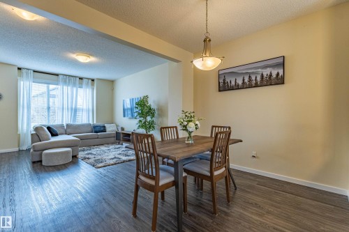 The property features an open living and dining area with dark wood-style flooring throughout - 2679 Maple Way, Edmonton, AB - Indoor