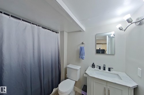 The bathroom features a modern vanity with a rectangular sink, a wall-mounted light fixture, and a toilet - 9328 106A Avenue, Edmonton, AB - Indoor Photo Showing Bathroom