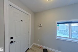 Entryway featuring a white paneled door with black hardware, light grey walls, and a window providing natural light - 